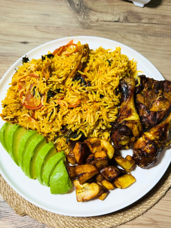 Serving one pan chicken and rice recipe with grilled chicken, fried plantains, and avocado on the side