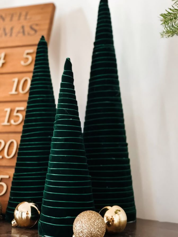Plush velvet Christmas trees in jewel-toned colors, arranged on cozy holiday display